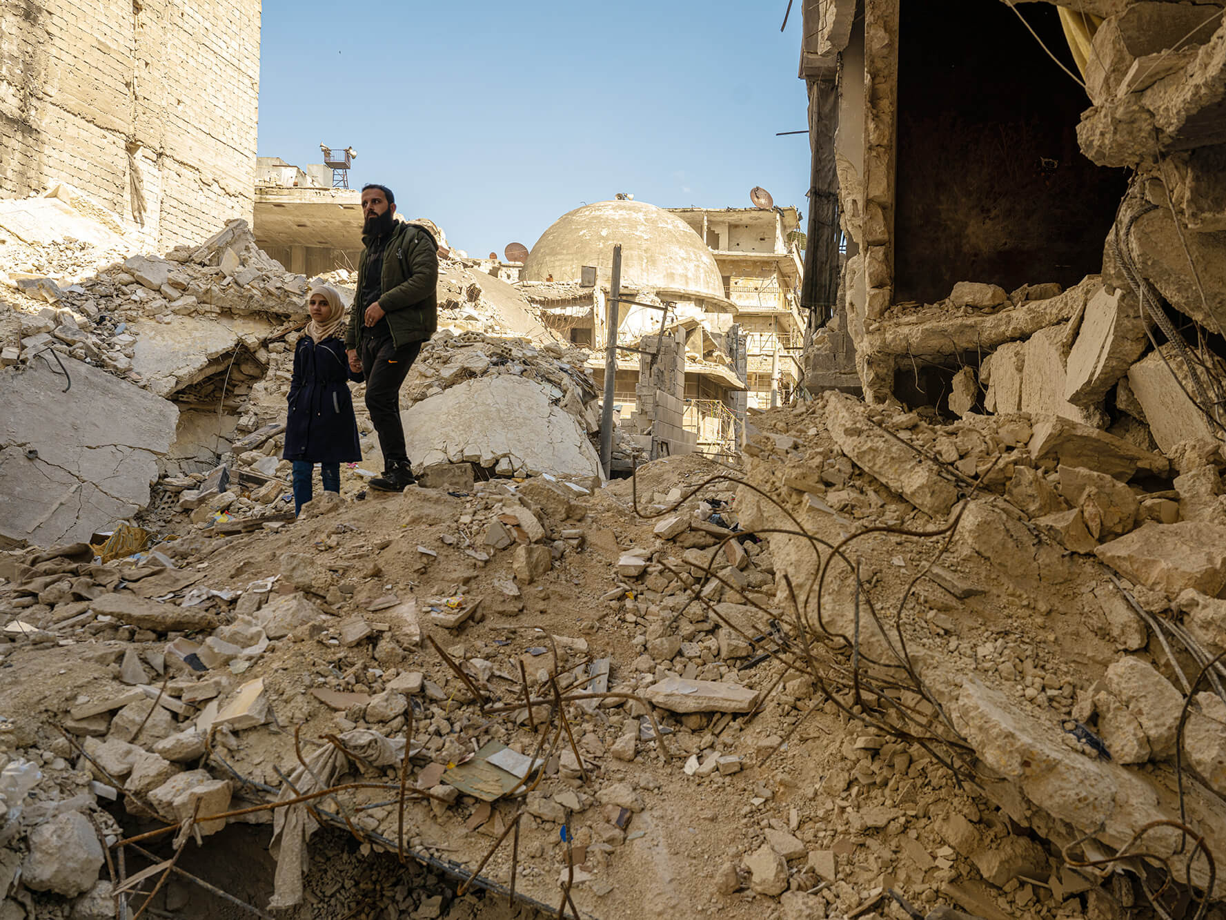 Ein Mädchen und ihr Vater auf Trümmern nach dem Erdbeben in Syrien.
