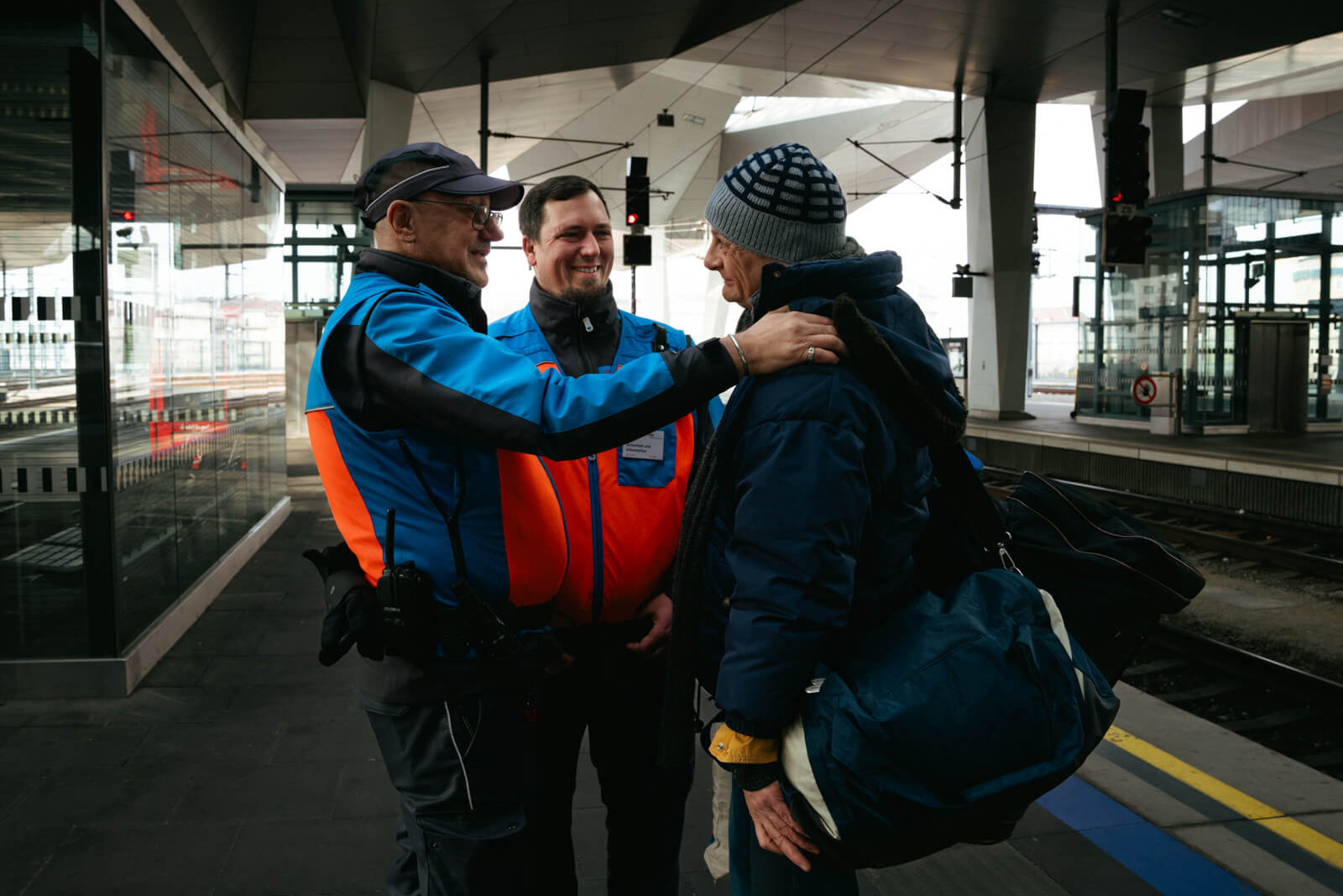 Zwei Mitarbeiter der ÖBB und ein obdachloser Mann auf einem Bahnsteig