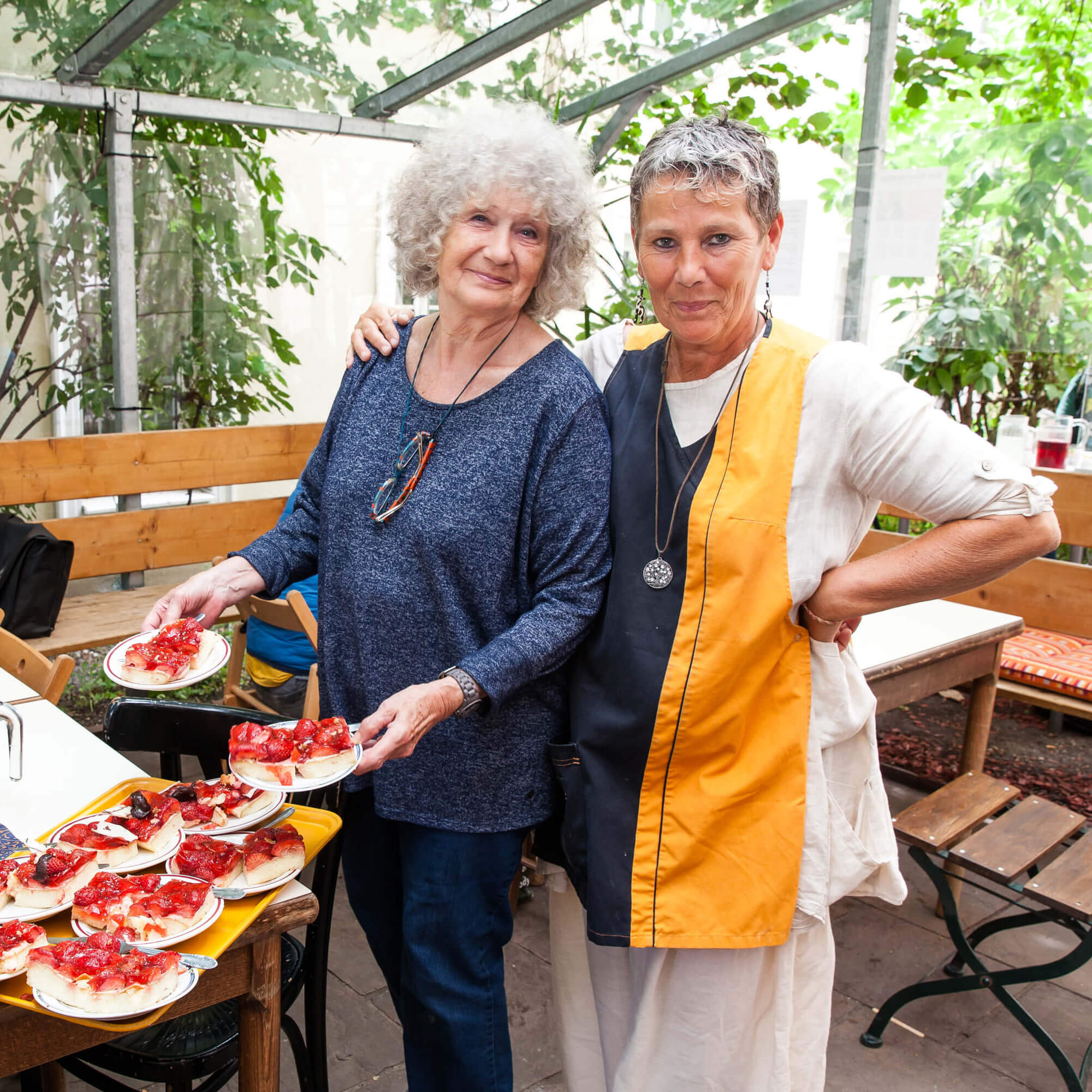 Zwei Frauen servieren Kuchen im Gastgarten des Häferl der Diakonie.