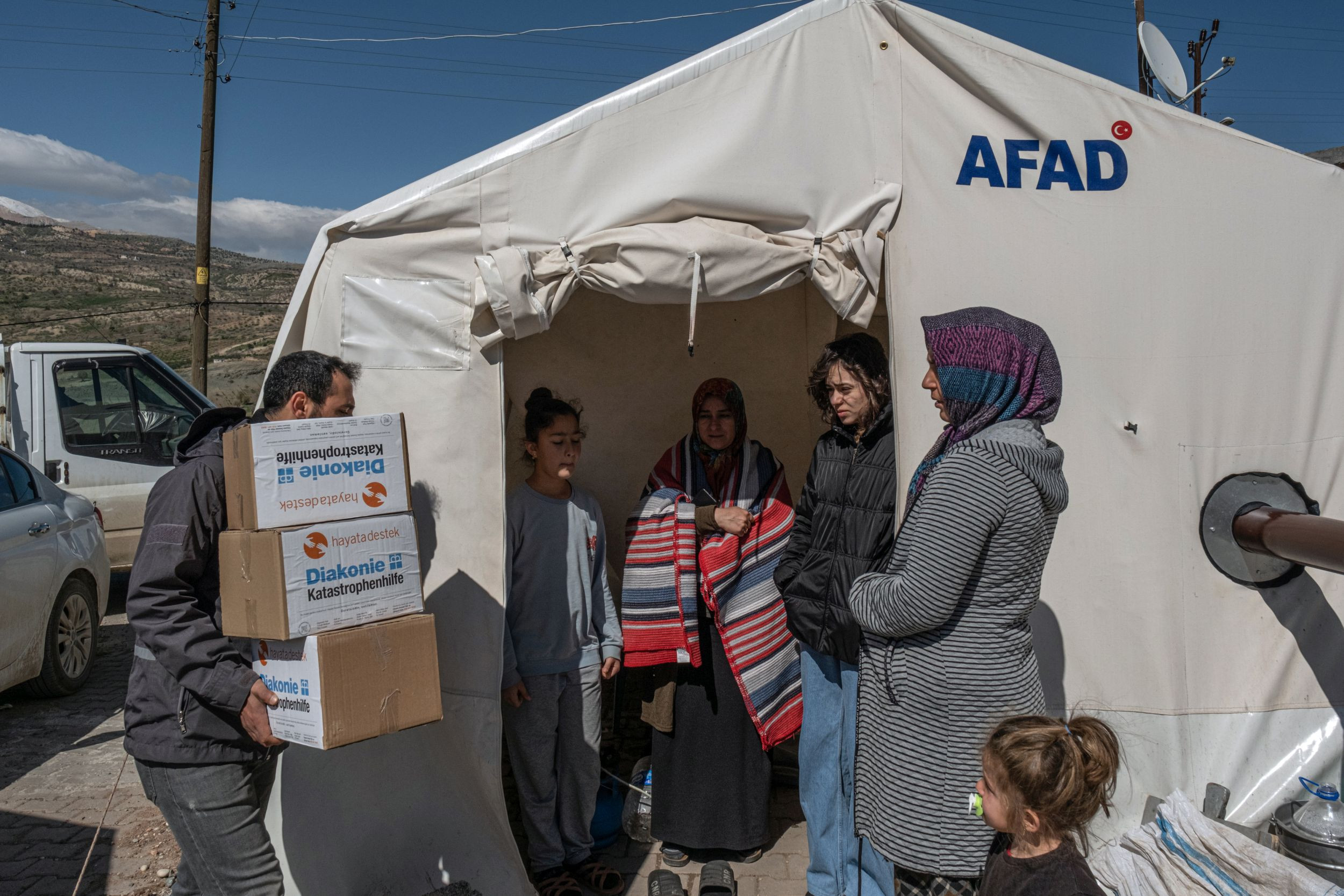Mann bringt Hilfsgüter zu Zeltunterkunft von Menschen, die beim Erdbeben in der Türkei ihr Zuhause verloren haben