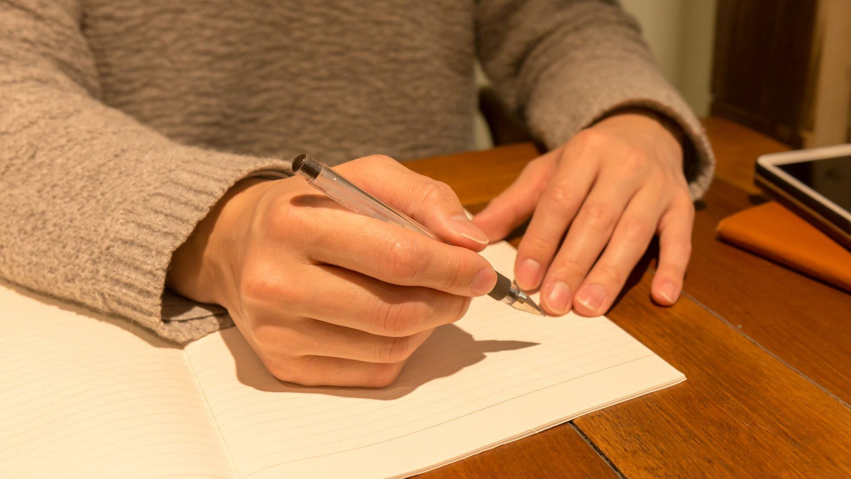 Hand hält einen Stift um in ein Heft zu schreiben