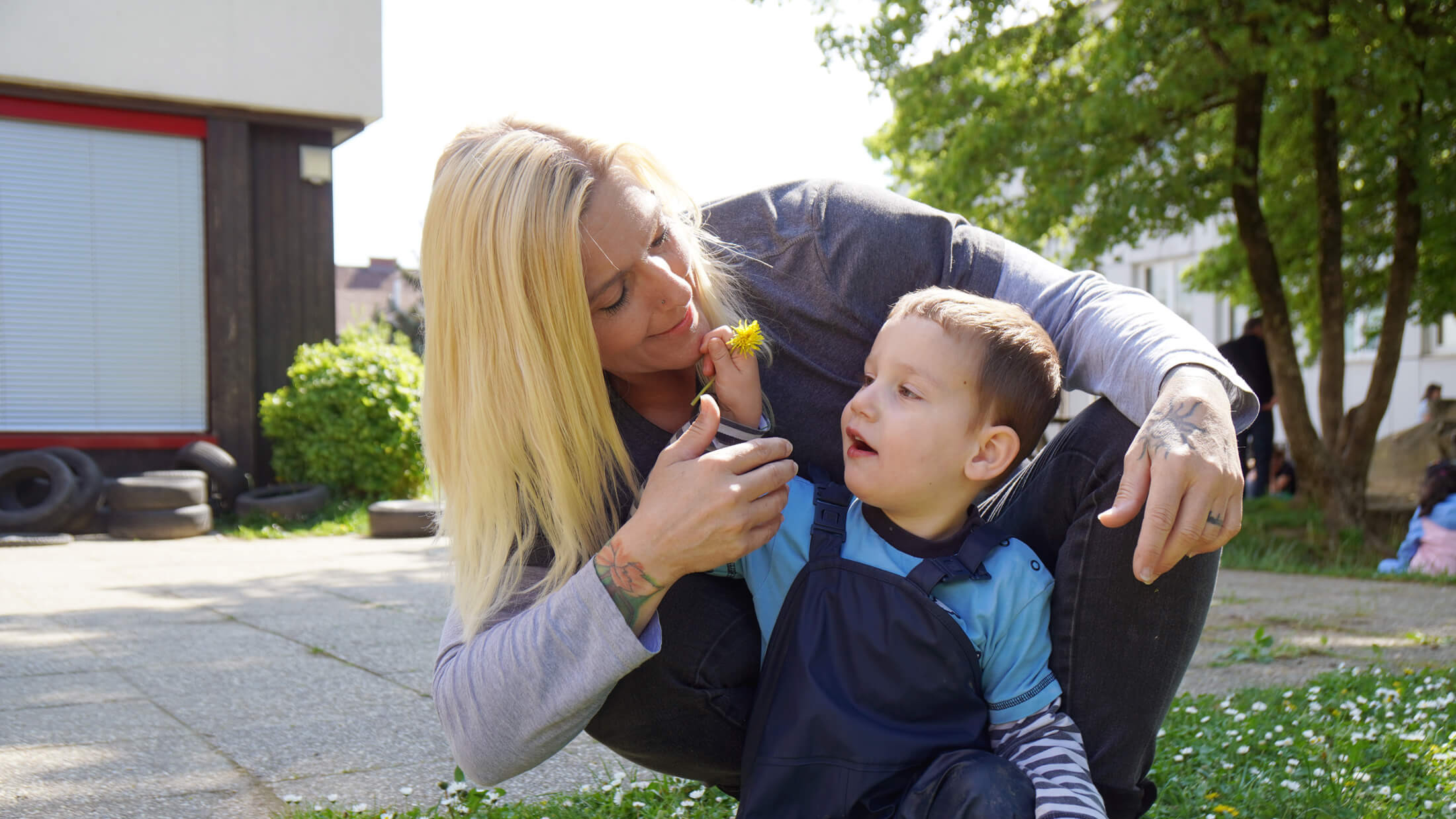 Hoffnungsträger Matteo zeigt Hoffnunsträgerin Claudia eine gelbe Blume.