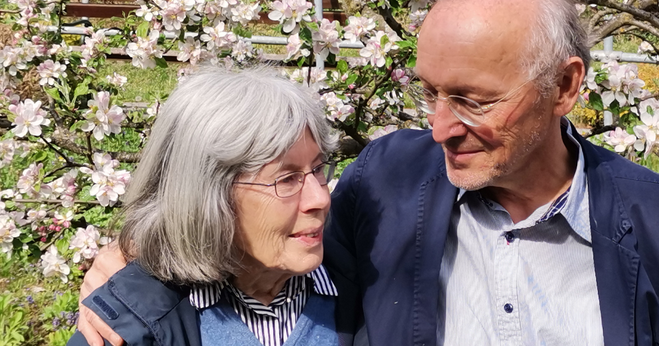 Ute und Jörg Uitz stehen lächelnd vor einem blühenden Baum.