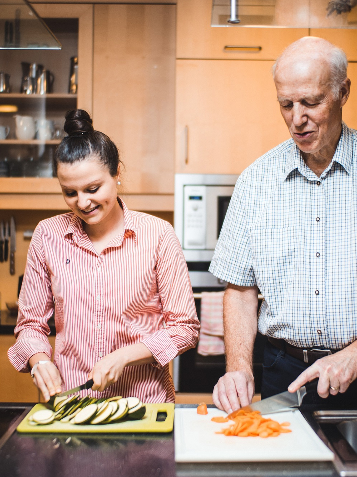 Eine junge Frau und ein älterer Mann kochen gemeinsam.