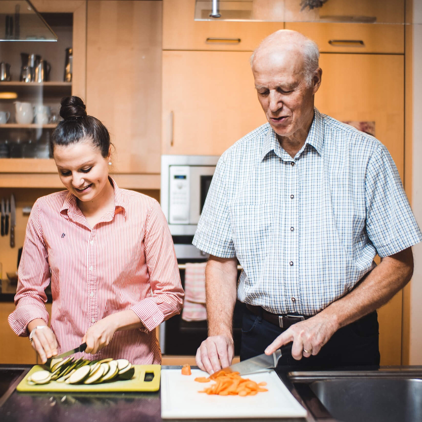 Eine junge Frau und ein älterer Mann kochen gemeinsam.