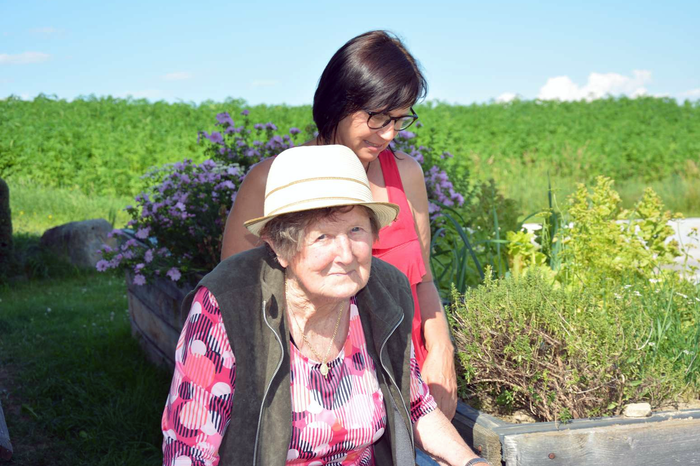 Augustine Undesser und Begleitung im Garten, im Hintergrund sind Hochbeete zu sehen.